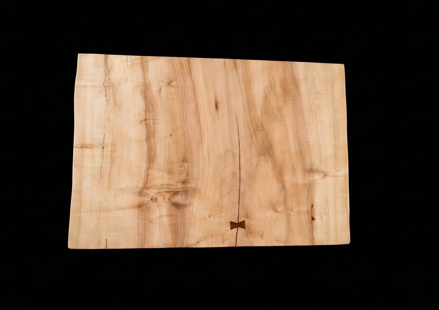 Maple table top showing live-edge details and bowtie inlay